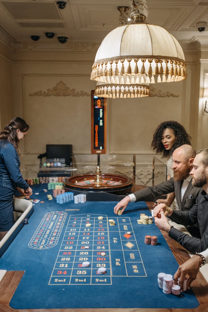 A group of diverse adults play at a sophisticated casino roulette table indoors.